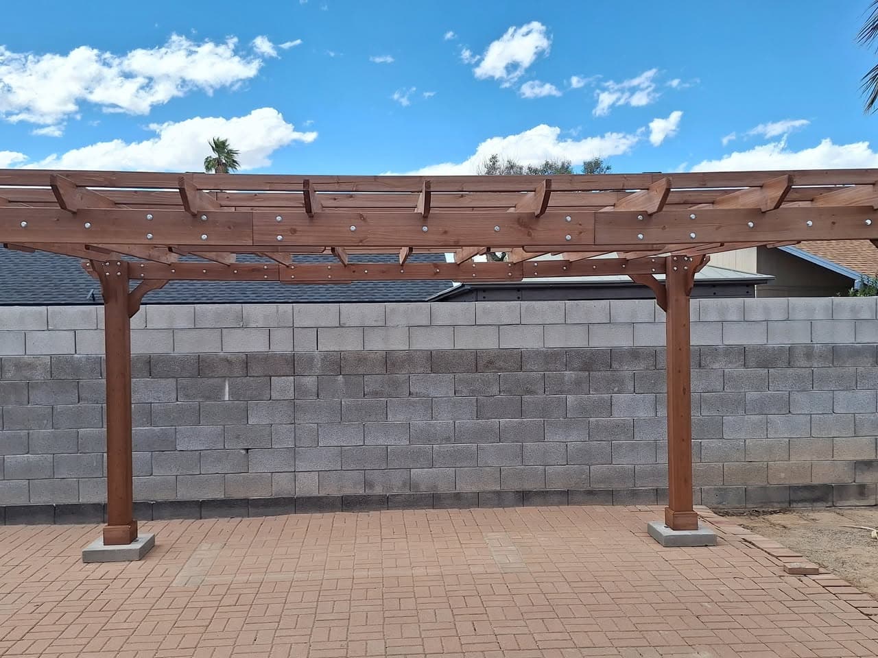 Freestanding wood pergola viewed straight on across a backyard patio